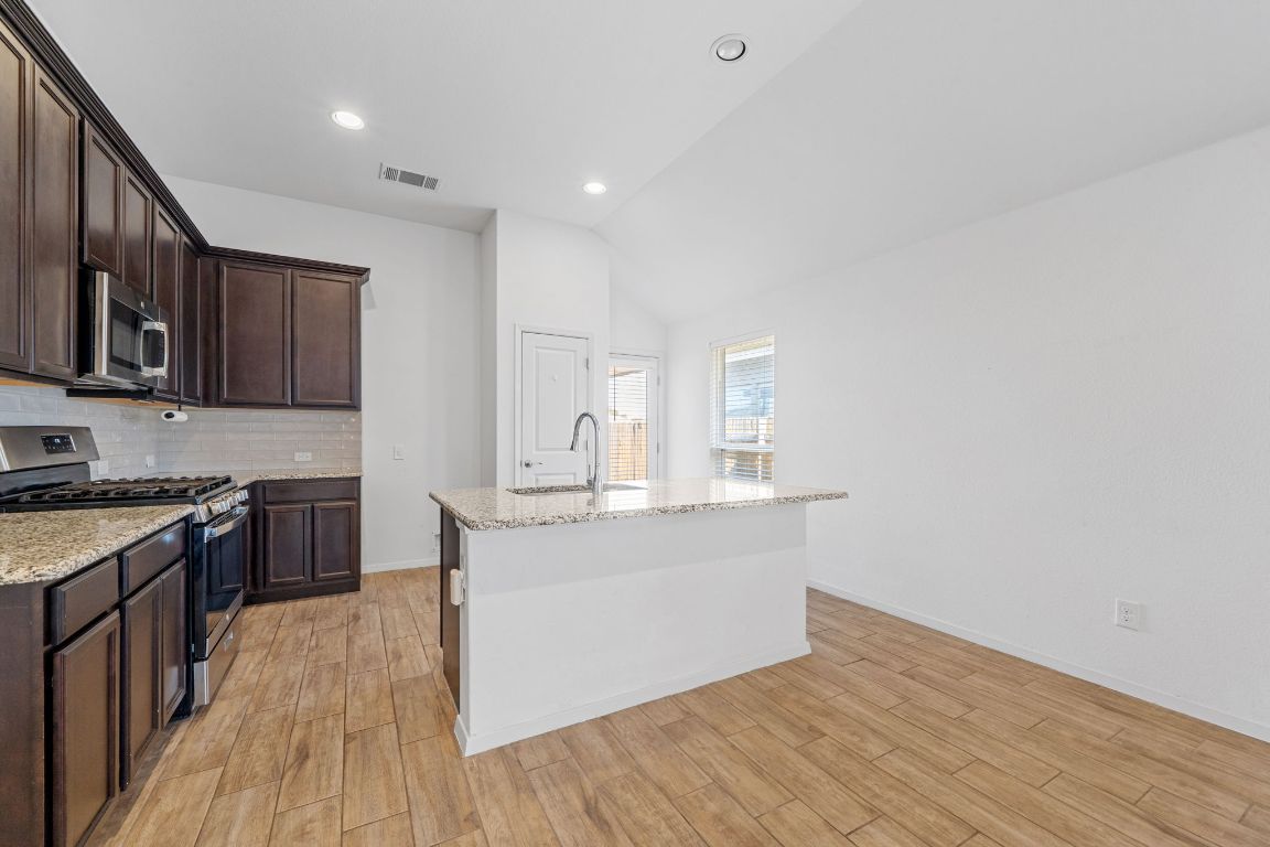 219 Trailside Lane Bastrop, TX 78602 - Photo 6 of 19 a kitchen with stainless steel appliances granite countertop a stove top oven a sink dishwasher and a microwave oven on granite countertops