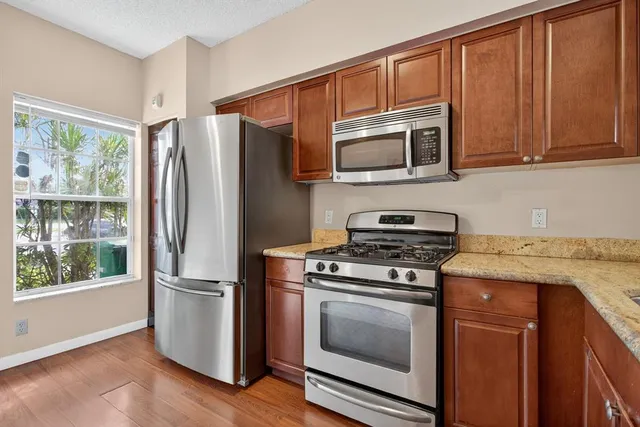a kitchen with granite countertop wooden cabinets stainless steel appliances and a window