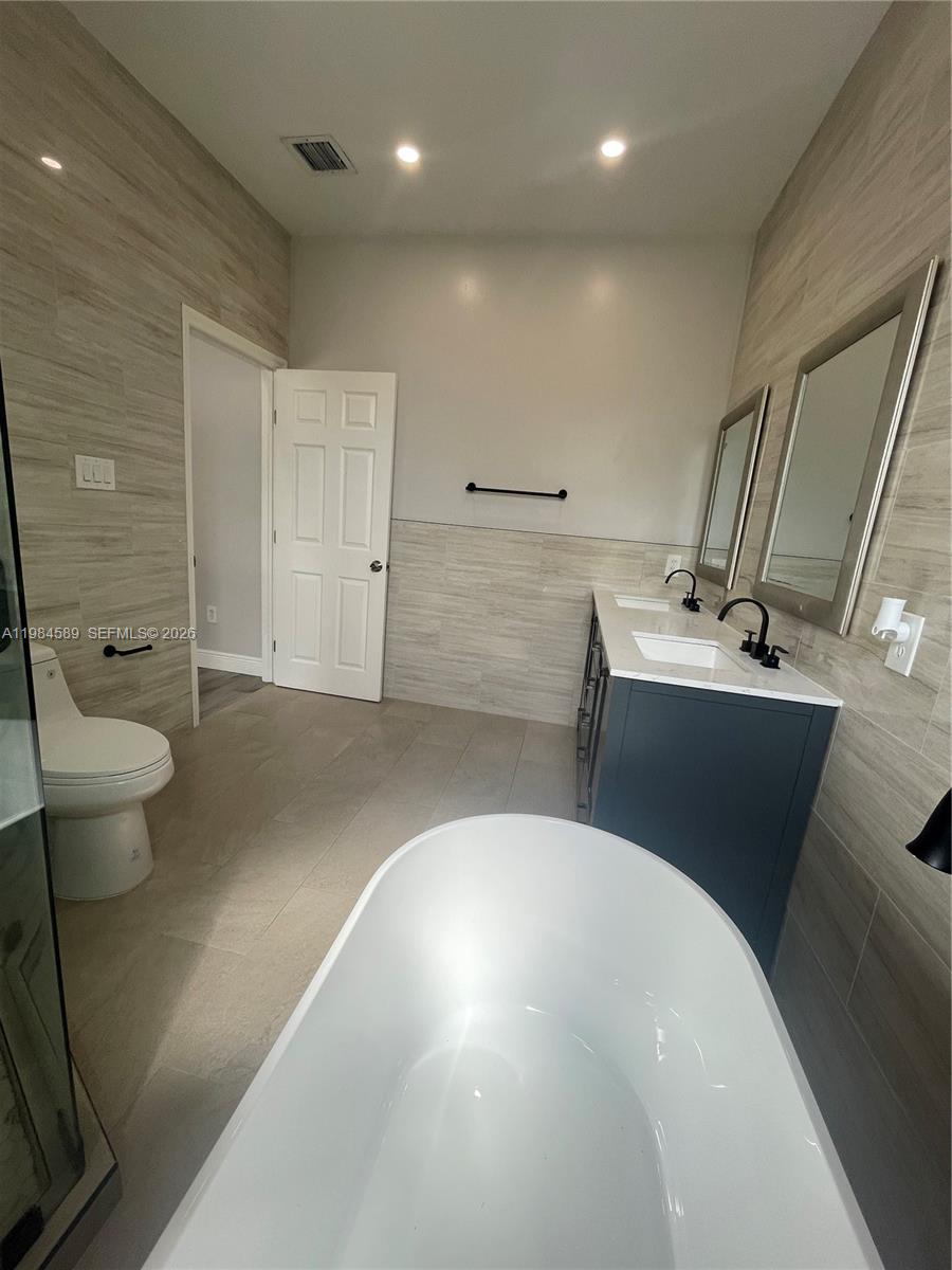 8900 Southwest 226th Terrace Cutler Bay, FL 33190 - Photo 25 of 40 a bathroom with a sink a toilet and a large mirror