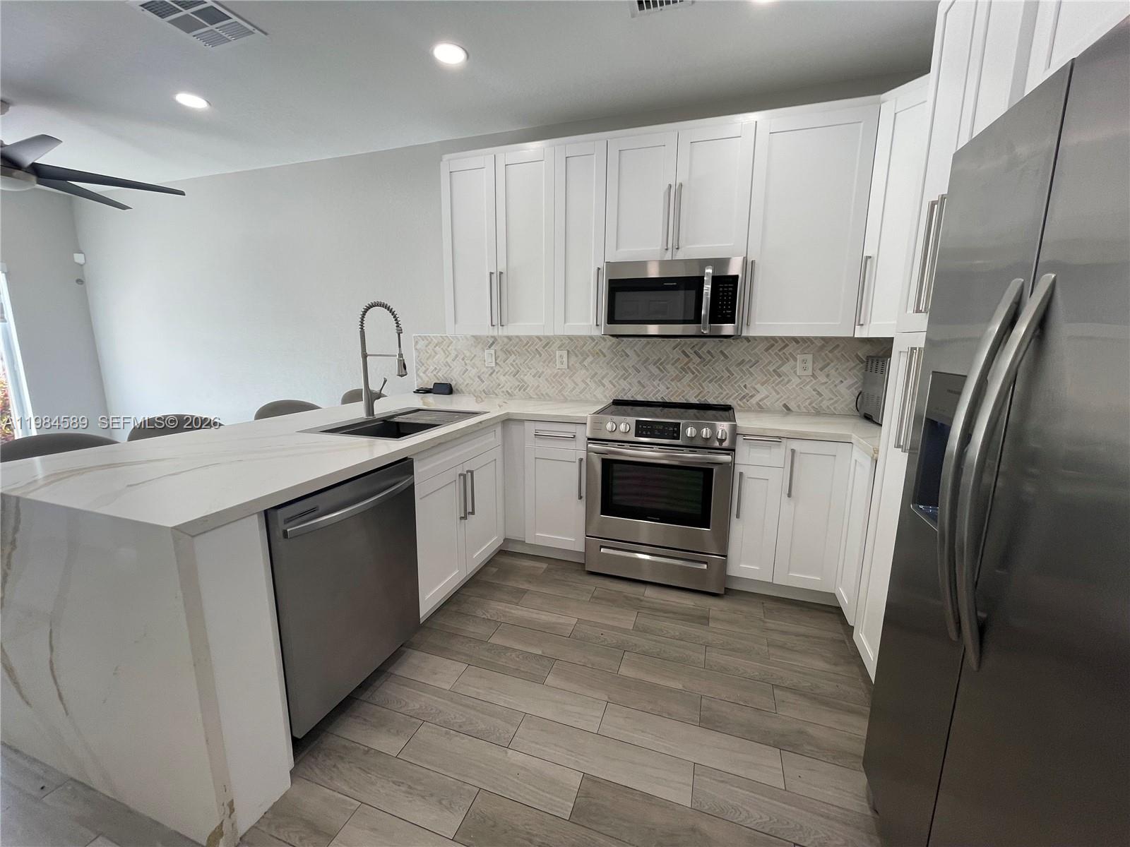 8900 Southwest 226th Terrace Cutler Bay, FL 33190 - Photo 5 of 40 a kitchen with stainless steel appliances granite countertop a sink stove and refrigerator