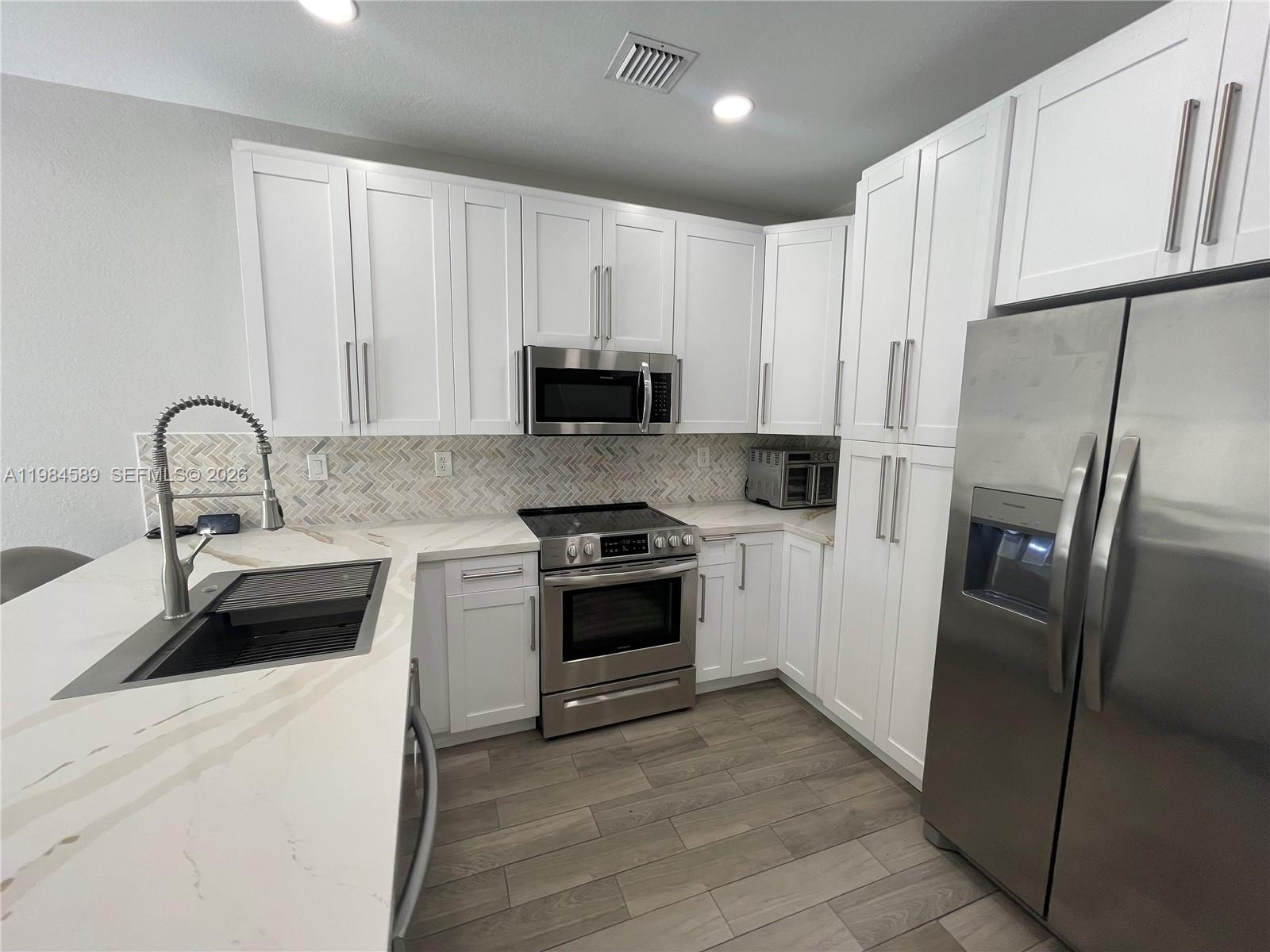 8900 Southwest 226th Terrace Cutler Bay, FL 33190 - Photo 6 of 40 a kitchen with a refrigerator sink and cabinets