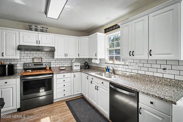 a kitchen with stainless steel appliances granite countertop a sink a stove and cabinets