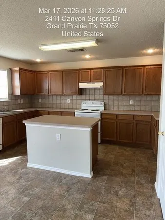 a view of a kitchen with a sink wooden cabinets and a refrigerator