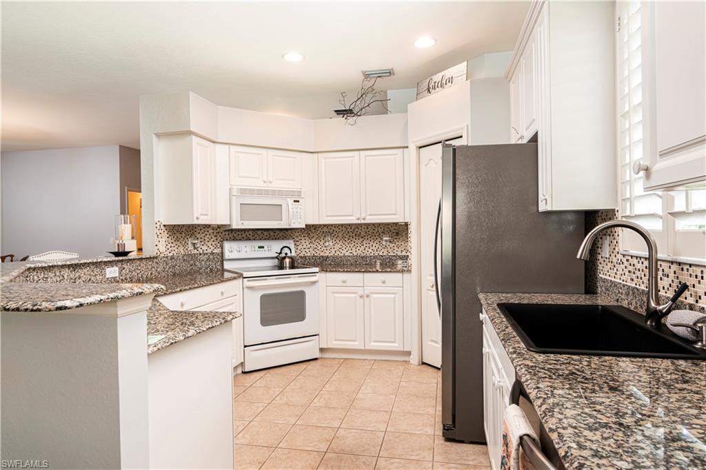 20058 Serre Drive Estero, FL 33928 - Photo 10 of 22 a kitchen with granite countertop a sink stainless steel appliances and white cabinets
