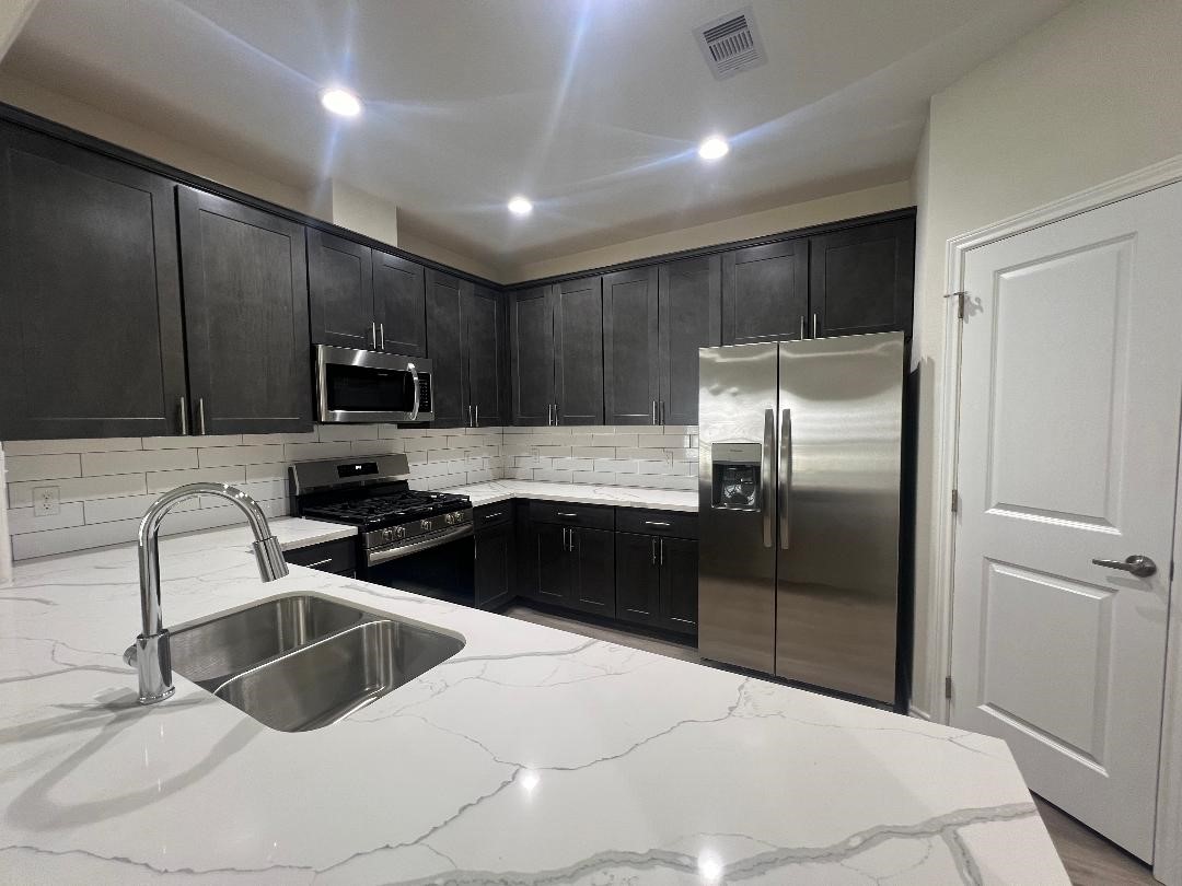 851 A Arbor Pnes Court Conroe, TX 77303 - Photo 3 of 13 a kitchen with granite countertop a refrigerator and a sink