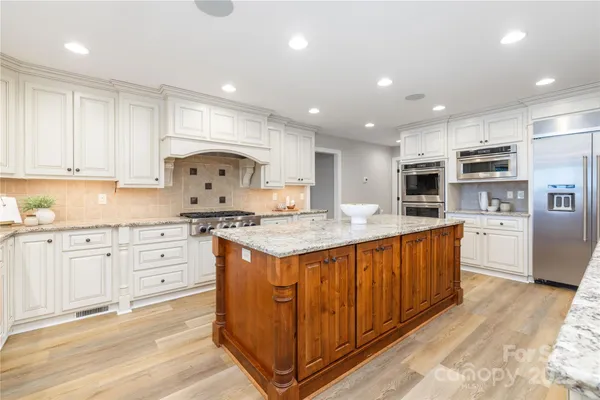 a kitchen with stainless steel appliances granite countertop a stove a sink and a refrigerator