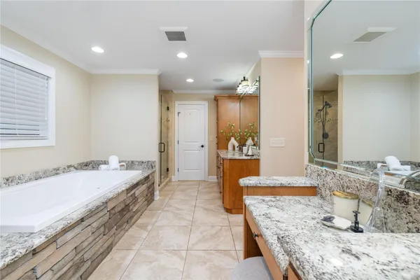 a large bathroom with a granite countertop tub a sink and a large mirror