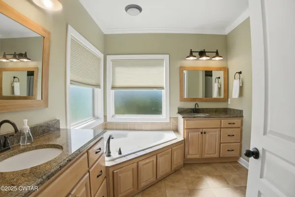 a bathroom with a granite countertop tub sink and mirror