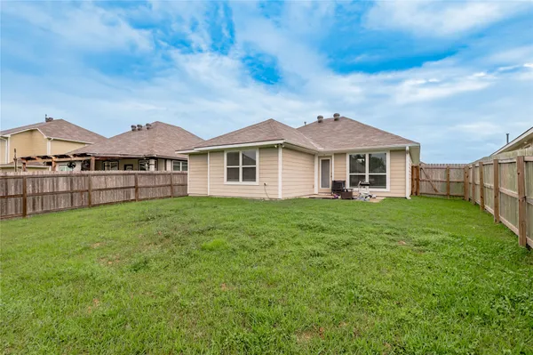 a view of a yard in front of a house with wooden fence