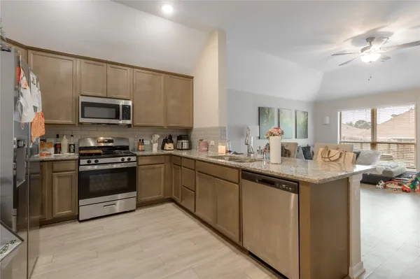 a kitchen with stainless steel appliances granite countertop a stove top oven a sink dishwasher a dining table and chairs with wooden floor