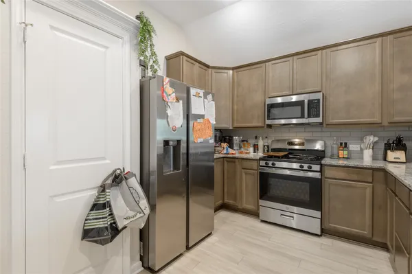 a kitchen with granite countertop a refrigerator and a stove top oven