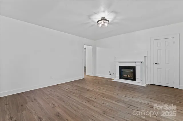 a view of empty room with wooden floor and fireplace