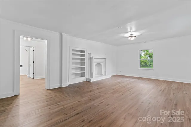 an empty room with wooden floor chandelier fan and windows