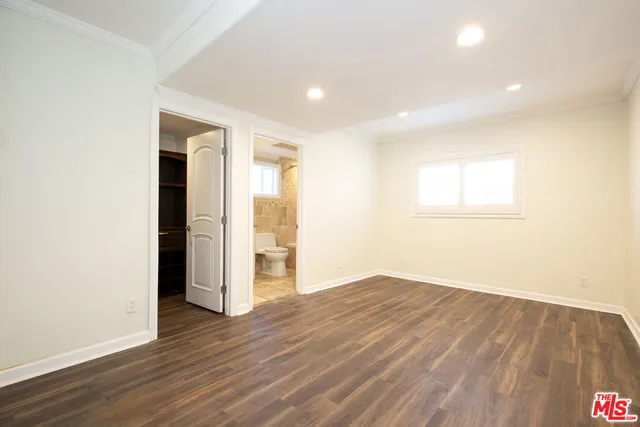 a view of an empty room with wooden floor and closet