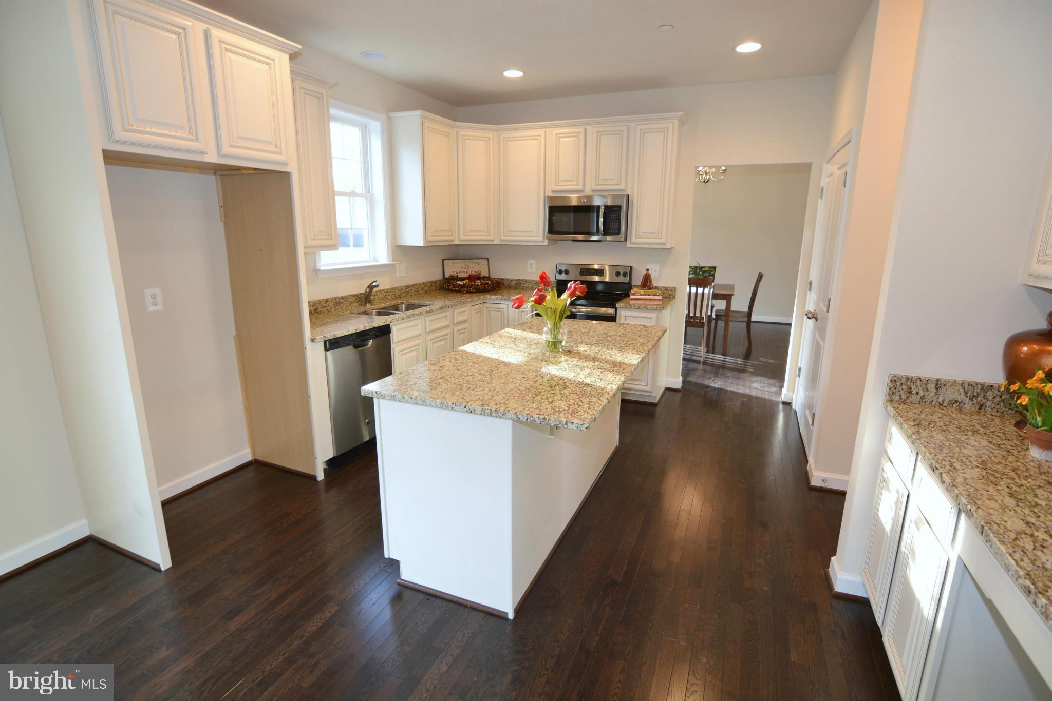1217 Shesley Road Mayo, MD 21037 - Photo 9 of 30 a kitchen with kitchen island granite countertop wooden floors white cabinets and stainless steel appliances