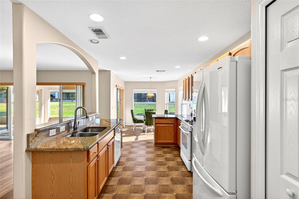1706 Southwest 156th Lane Ocala, FL 34473 - Photo 10 of 44 a large white kitchen with stainless steel appliances granite countertop a refrigerator a sink dishwasher a stove and a dining table with wooden floor