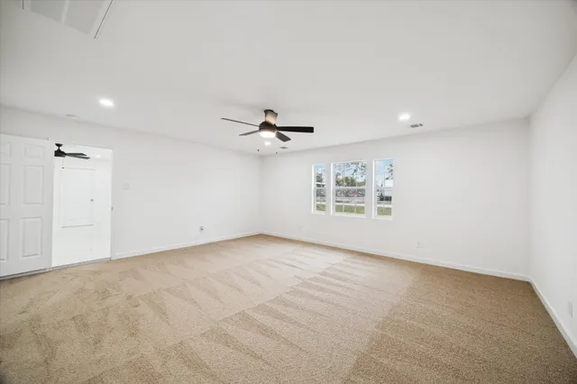 an empty room with a window and ceiling fan
