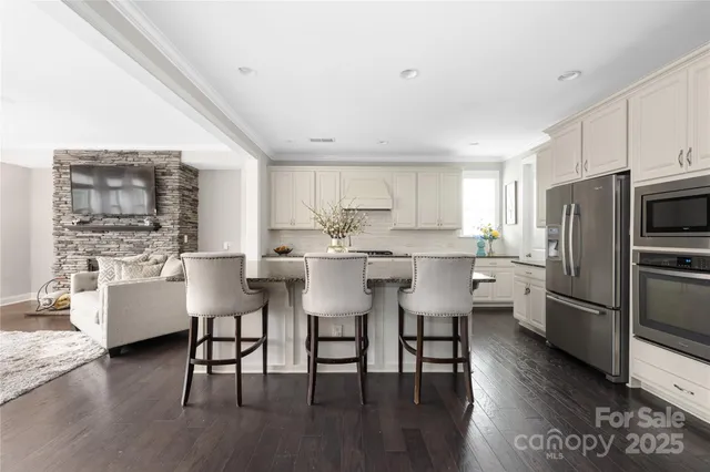 a kitchen with stainless steel appliances a dining table chairs microwave and sink