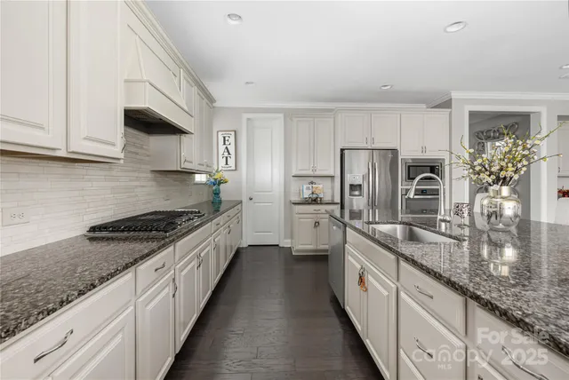 a large kitchen with granite countertop a sink stove refrigerator and cabinets