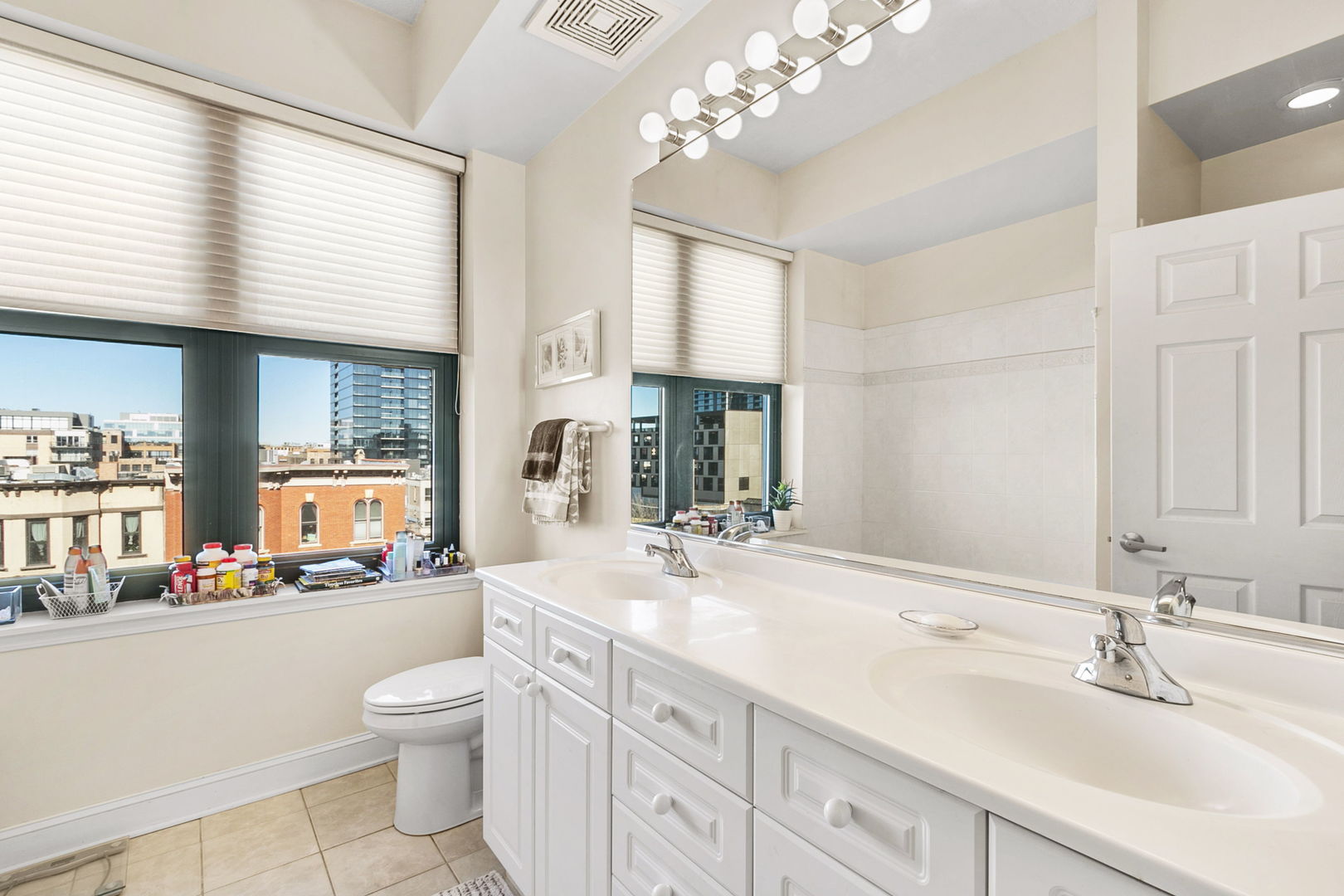 1301 West Washington Boulevard, Unit 508 Chicago, IL 60607 - Photo 12 of 17 a bathroom with a sink a large mirror and a toilet a window