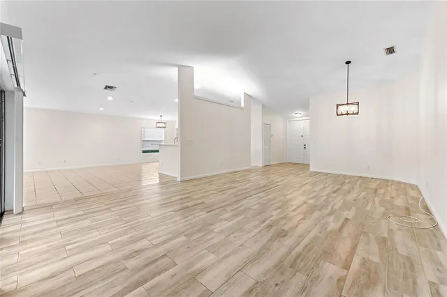a view of empty room with wooden floor and kitchen view