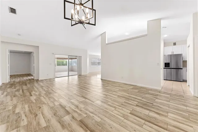 a view of empty room with wooden floor and kitchen view
