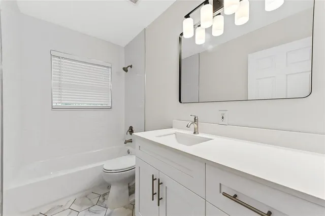 a bathroom with a toilet a sink a mirror and bathtub