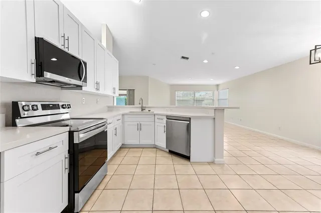 a kitchen with stainless steel appliances granite countertop a stove a sink and a microwave