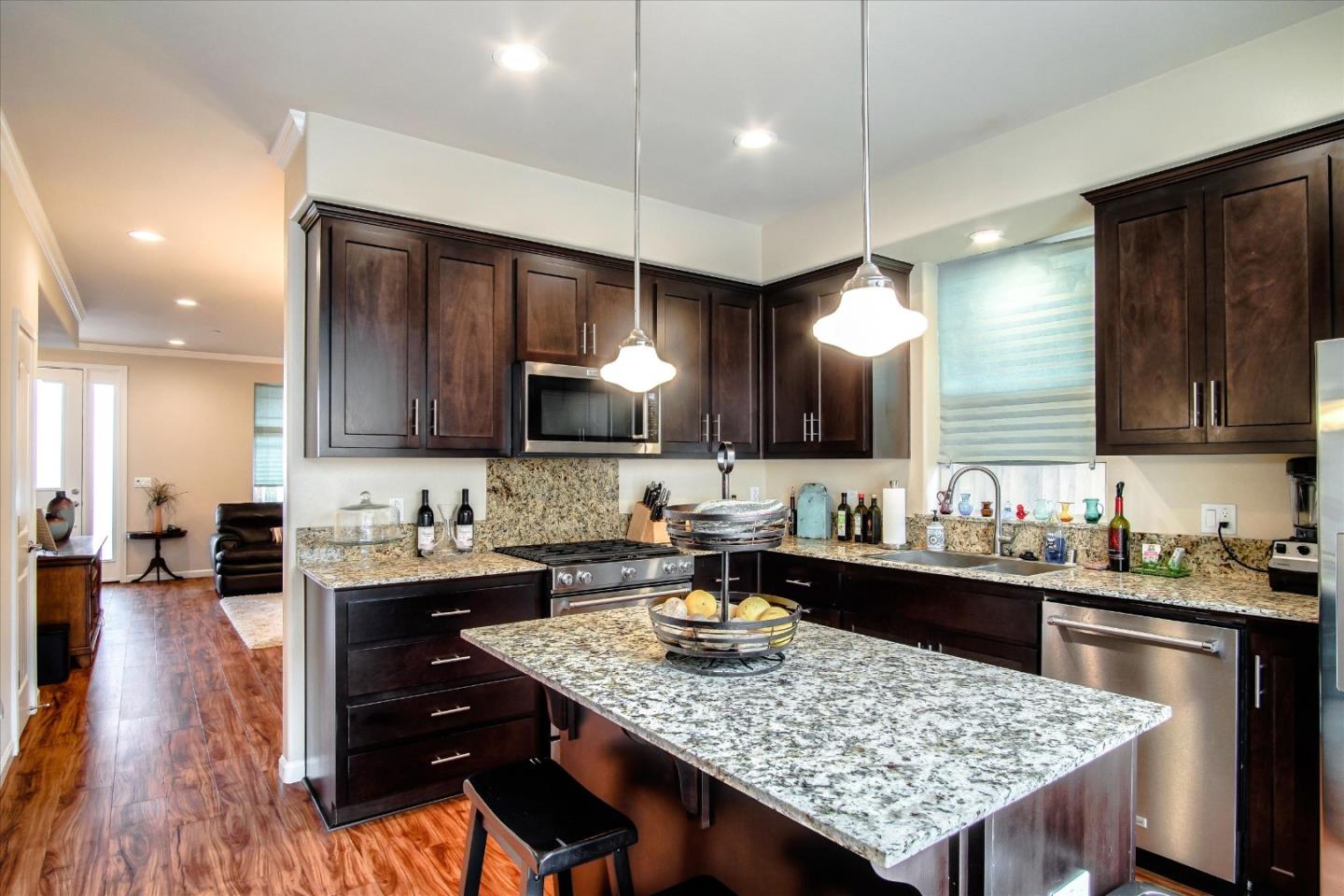 108 Springtime Circle Hollister, CA 95023 - Photo 2 of 36 a kitchen with a stove a refrigerator and a dining table with wooden floor
