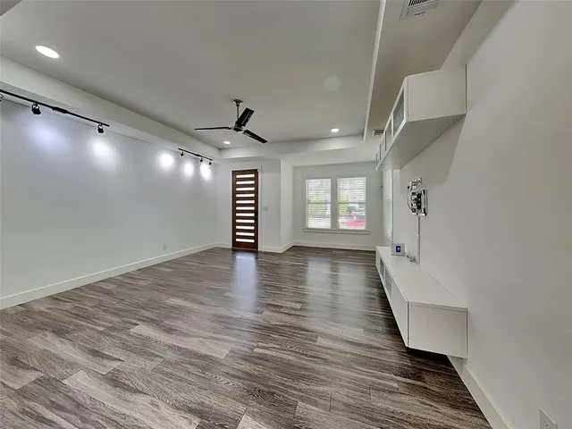 a view of an empty room with a window and wooden floor