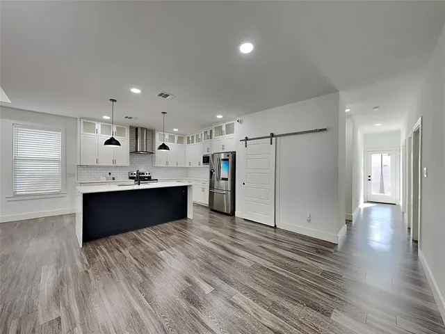 a large kitchen with a sink and dishwasher a refrigerator with wooden floors