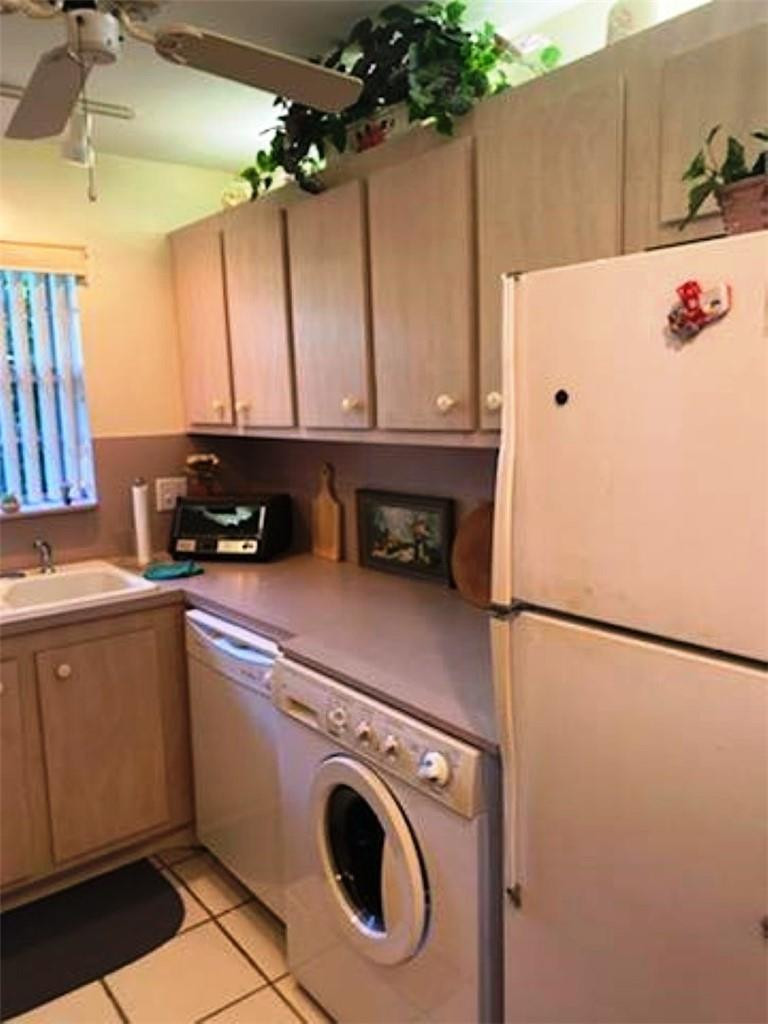 1124 Northwest 13th Street, Unit 106A Boca Raton, FL 33486 - Photo 3 of 8 a kitchen with a refrigerator a stove top oven a sink and a dishwasher