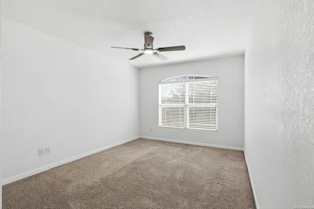 an empty room with a window and a fan