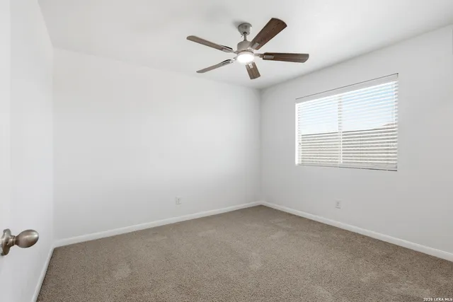 an empty room with a window and a fan