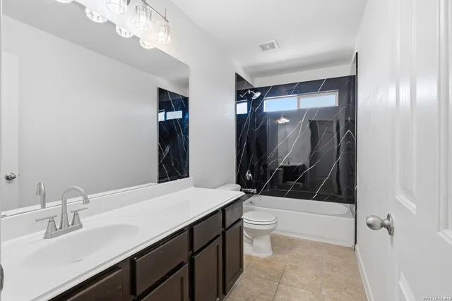 a bathroom with a sink a toilet a mirror and shower