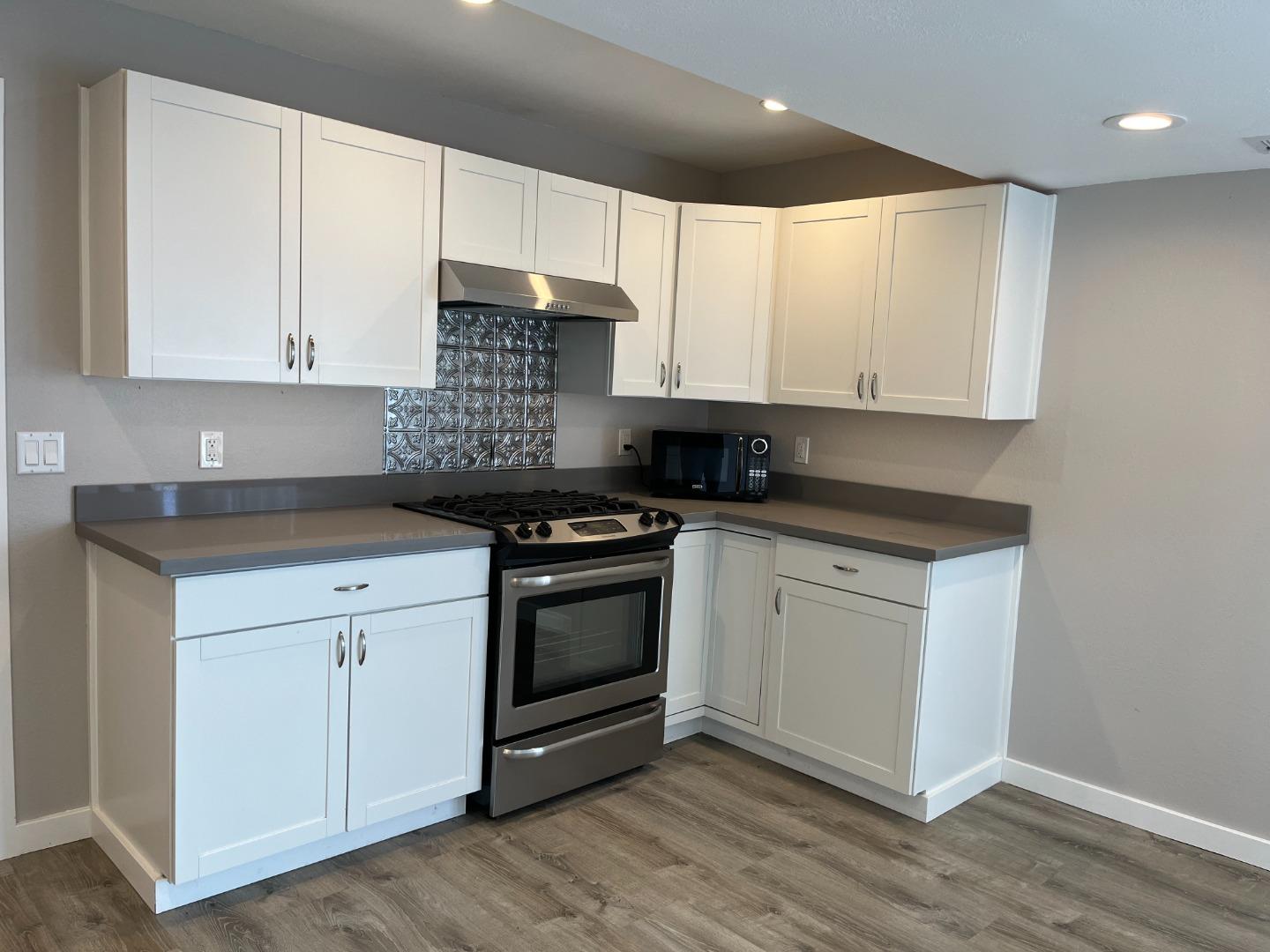 5 Malavear Court, Unit INLAW Pacifica, CA 94044 - Photo 5 of 13 a kitchen with granite countertop white cabinets and stainless steel appliances
