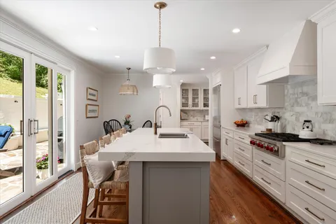 a kitchen with stainless steel appliances granite countertop a stove a sink a dining table and chairs with wooden floor