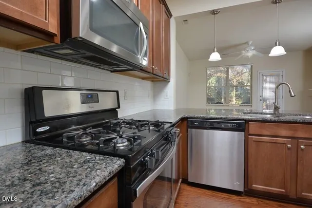 a kitchen with stainless steel appliances granite countertop a stove a sink and a microwave