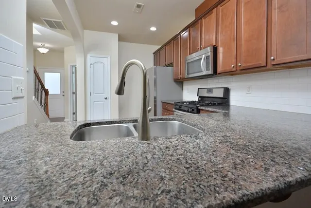 a kitchen with kitchen island granite countertop a sink a stove and cabinets