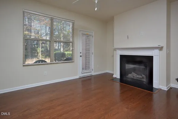 an empty room with wooden floor fireplace and windows