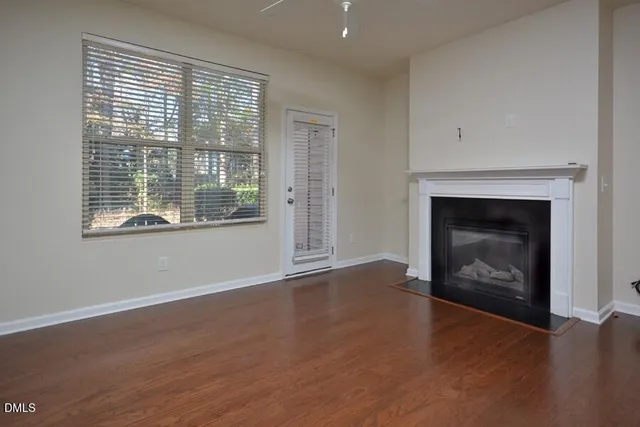 an empty room with wooden floor fireplace and windows
