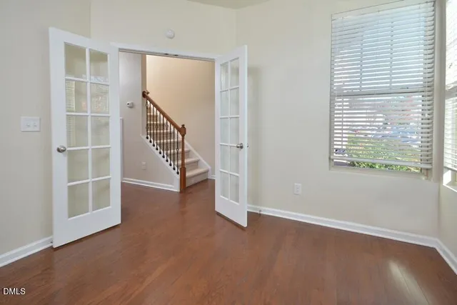 an empty room with wooden floor and windows