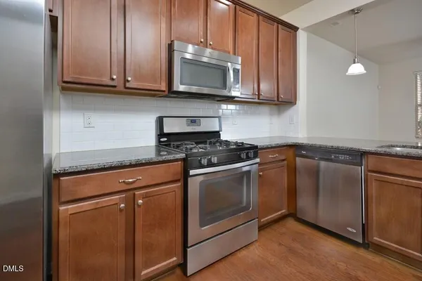 a kitchen with granite countertop wooden cabinets stainless steel appliances and a sink
