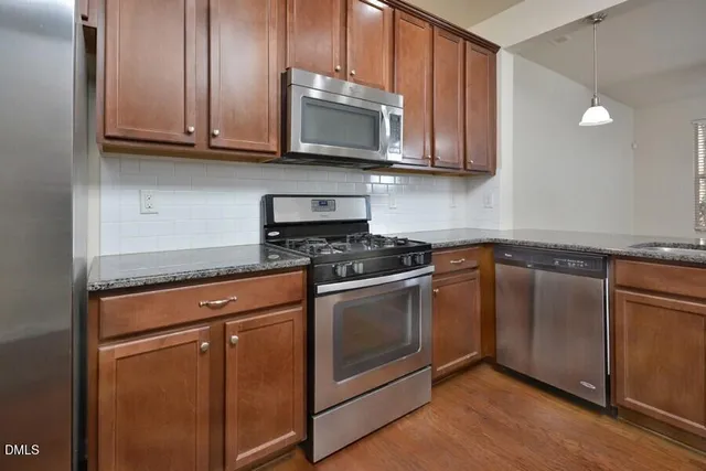 a kitchen with granite countertop wooden cabinets stainless steel appliances and a sink