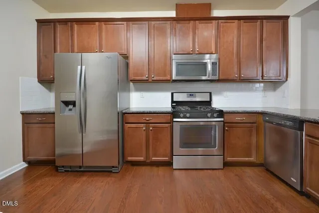 a kitchen with granite countertop a refrigerator stove and microwave