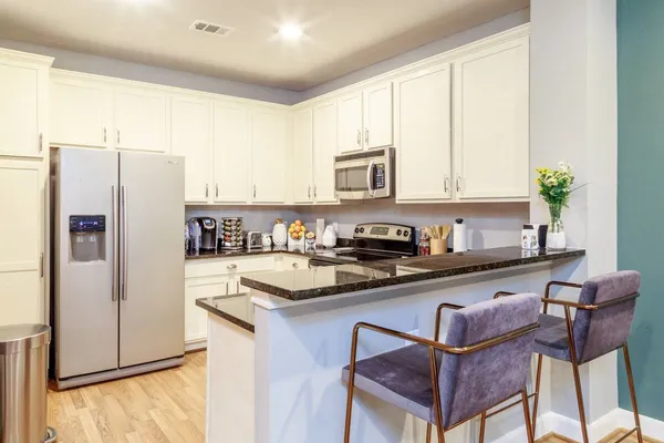 a kitchen with stainless steel appliances granite countertop a refrigerator a stove a sink and a microwave