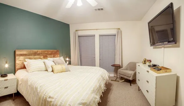 a bedroom with a bed and flat tv screen on the dresser