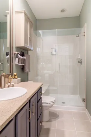 a bathroom with a granite countertop sink a toilet and shower