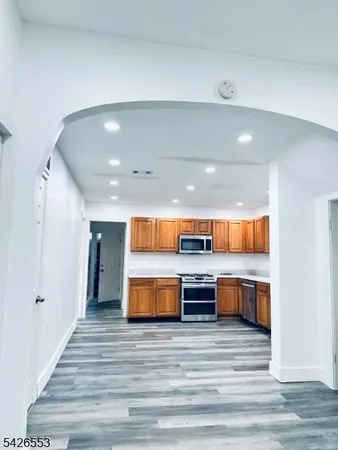 a room with stainless steel appliances wooden floor and view living room