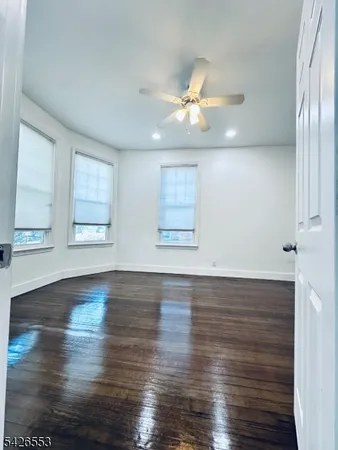 an empty room with wooden floor fan and windows